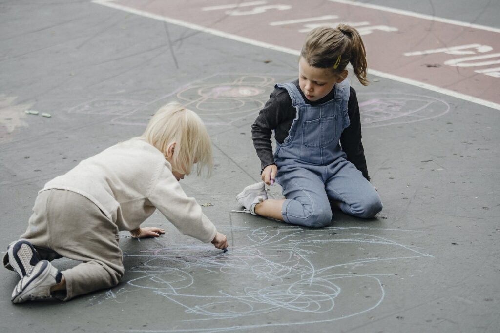 Adorable girls drawing on asphalt